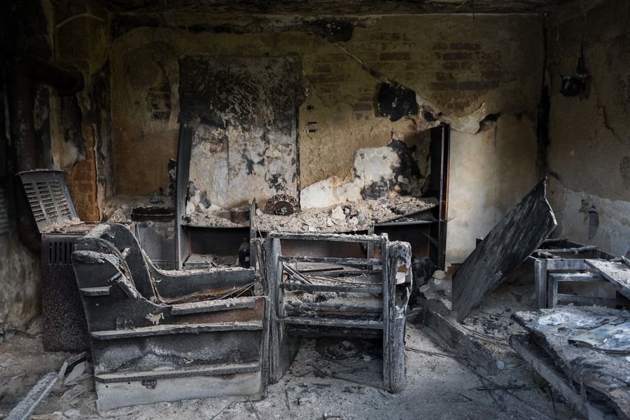 Charred interior of a room showing heavy fire and smoke damage on walls and furniture.