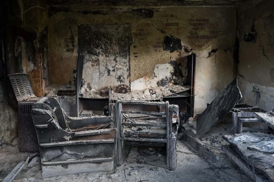 Charred interior of a room showing heavy fire and smoke damage on walls and furniture.