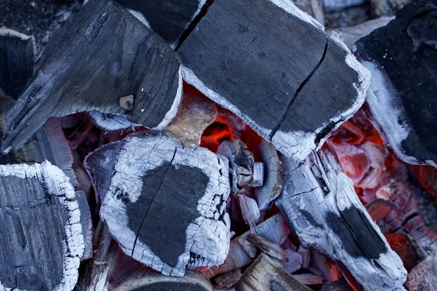 Fire-damaged kitchen interior with charred walls, blackened cabinets, and heavy soot residue around the stove area.